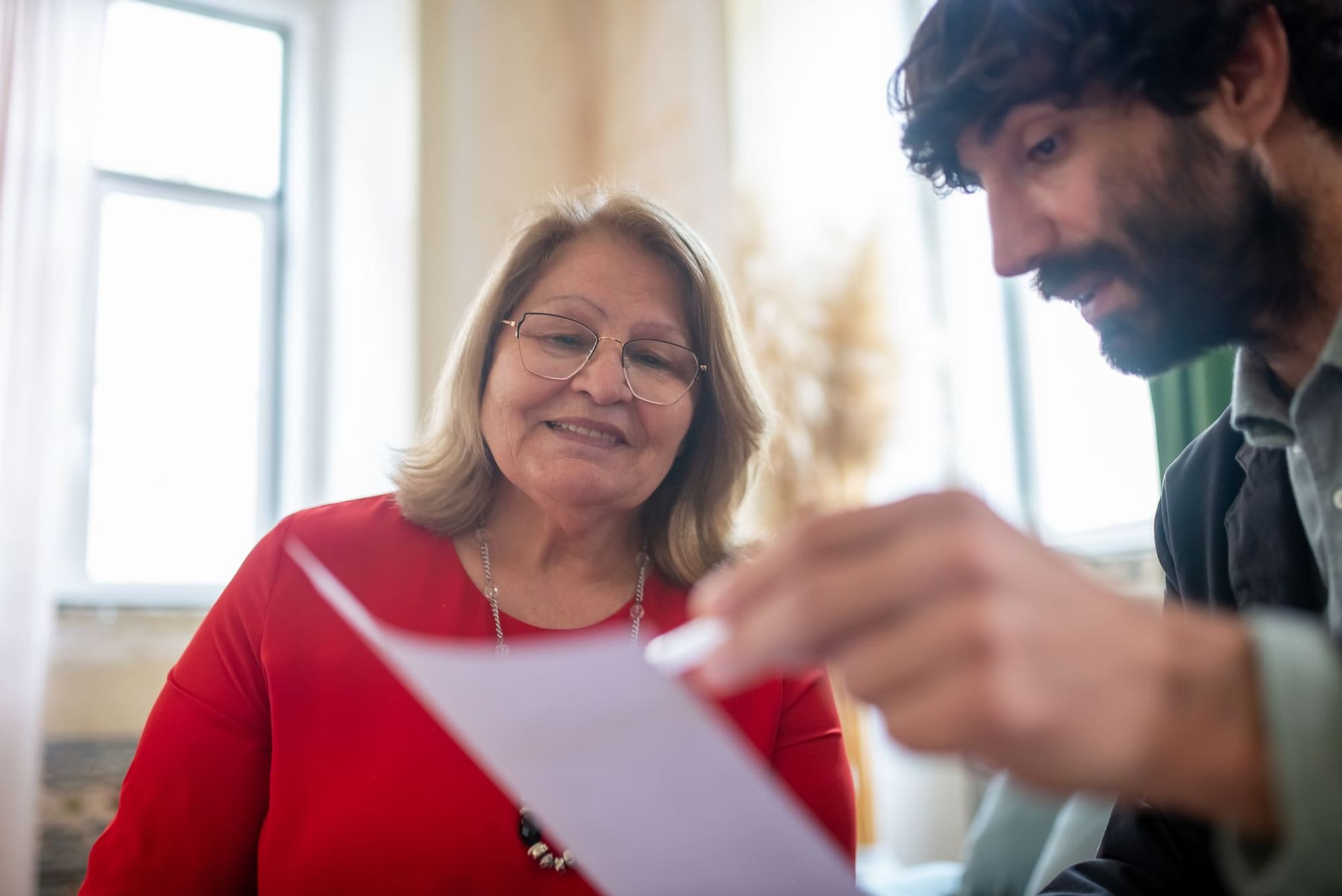 אישה מבוגרת בפגישה בביתה מעיינת במסמך יחד עם עורך דין